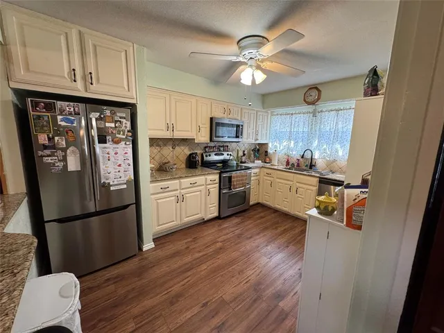 a kitchen with stainless steel appliances granite countertop a refrigerator a sink dishwasher a stove with wooden floor and cabinets