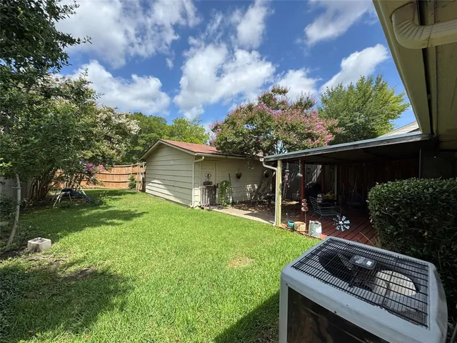 a view of a backyard with table and chairs potted plants and a large tree