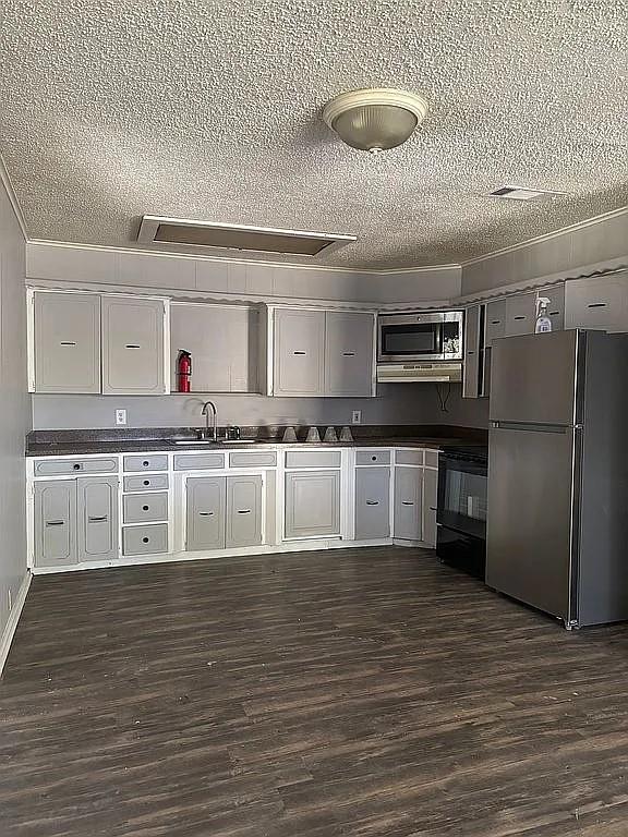 1711 Ash Street Commerce, TX 75428 - Photo 7 of 11 a large kitchen with stainless steel appliances granite countertop a stove and a refrigerator