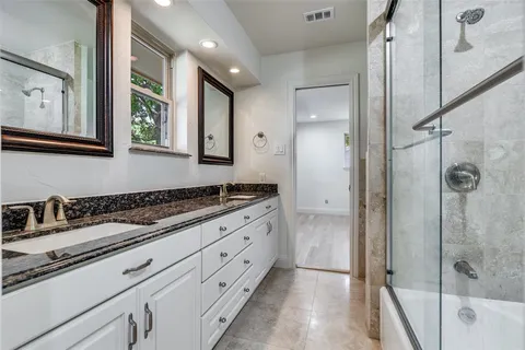 a bathroom with a granite countertop sink mirror and shower