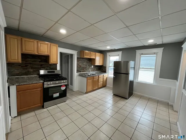 a kitchen with stainless steel appliances granite countertop a refrigerator and a stove top oven