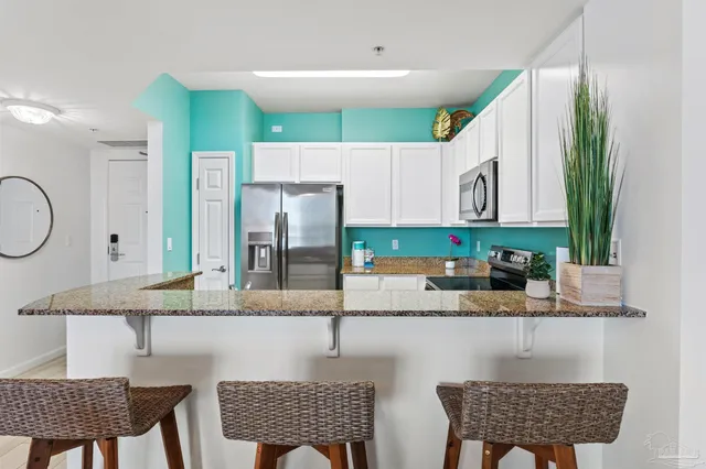 a kitchen with stainless steel appliances granite countertop a refrigerator a sink a stove a dining table and chairs