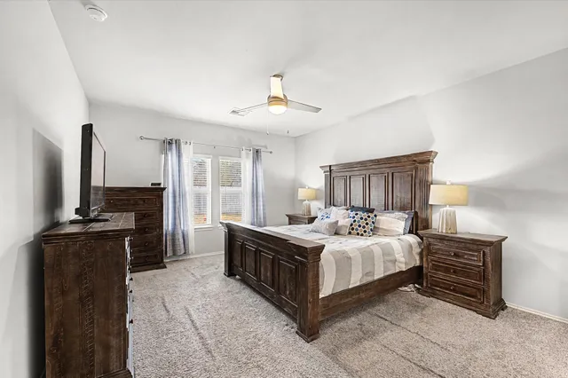 a bedroom with a bed dresser and a flat tv screen