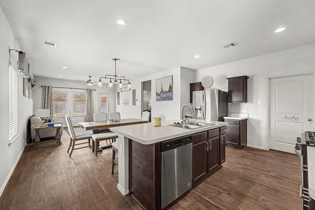 a kitchen with a stove a refrigerator a sink dishwasher with a dining table and chairs