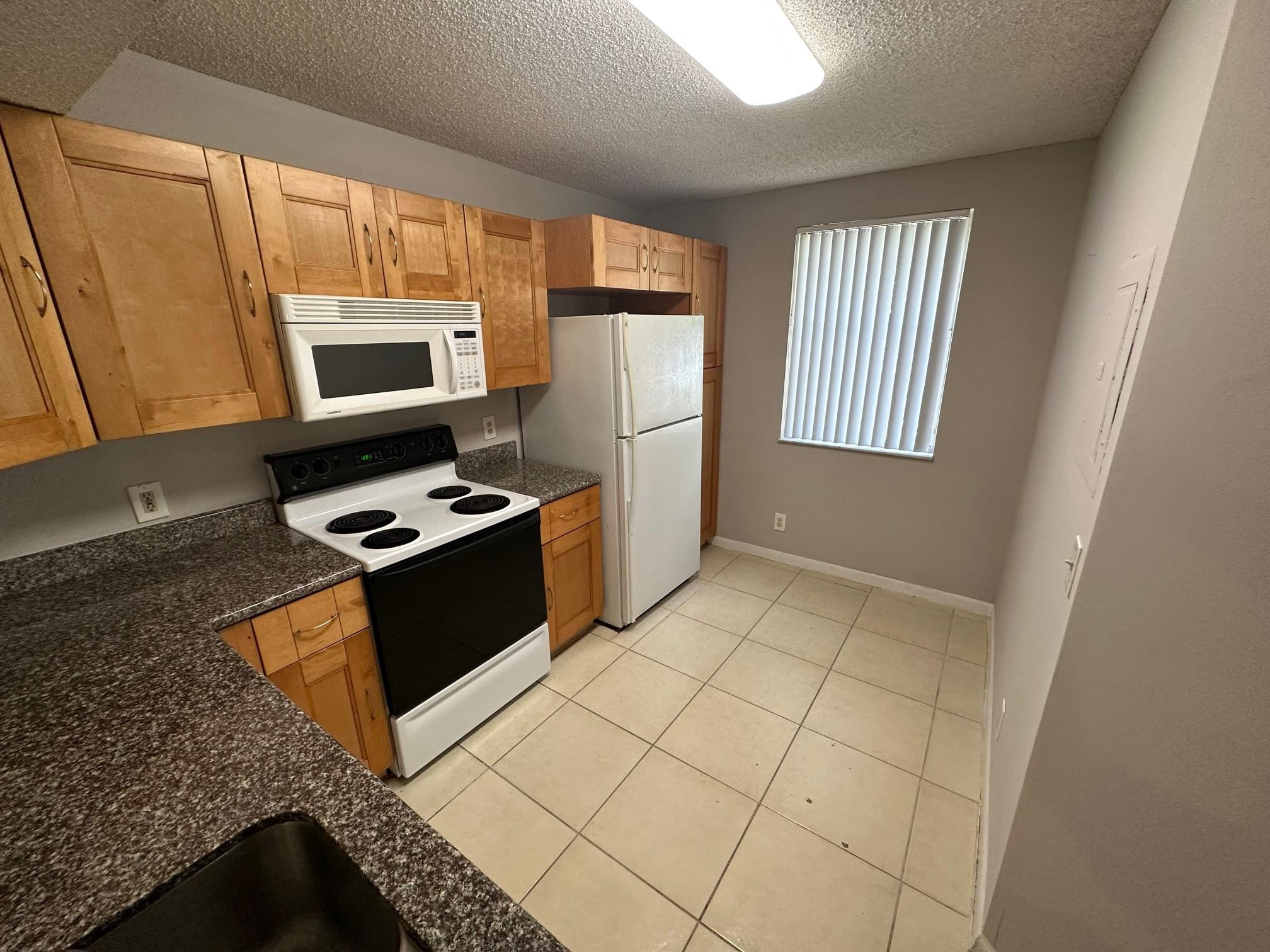 9001 Wiles Road Coral Springs, FL 33067 - Photo 6 of 10 a kitchen with stainless steel appliances granite countertop a stove a sink and a microwave