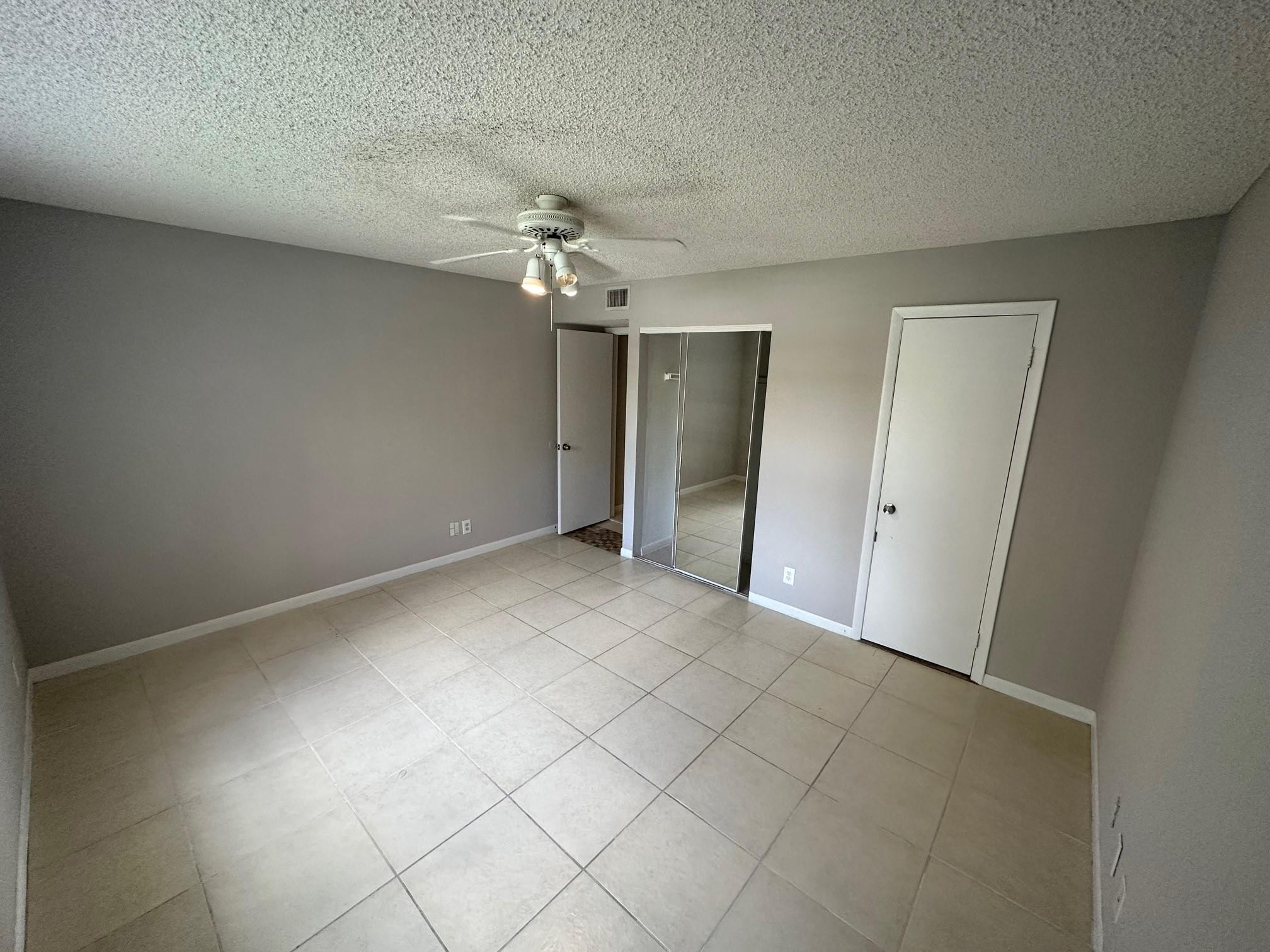 9001 Wiles Road Coral Springs, FL 33067 - Photo 9 of 10 an empty room with a chandelier fan and closet