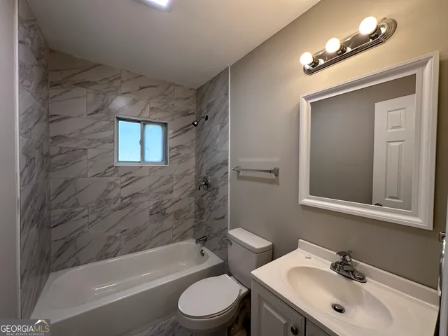 a bathroom with a toilet a sink a mirror a bathtub and shower
