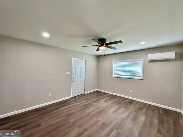 a view of an empty room with wooden floor and a ceiling fan