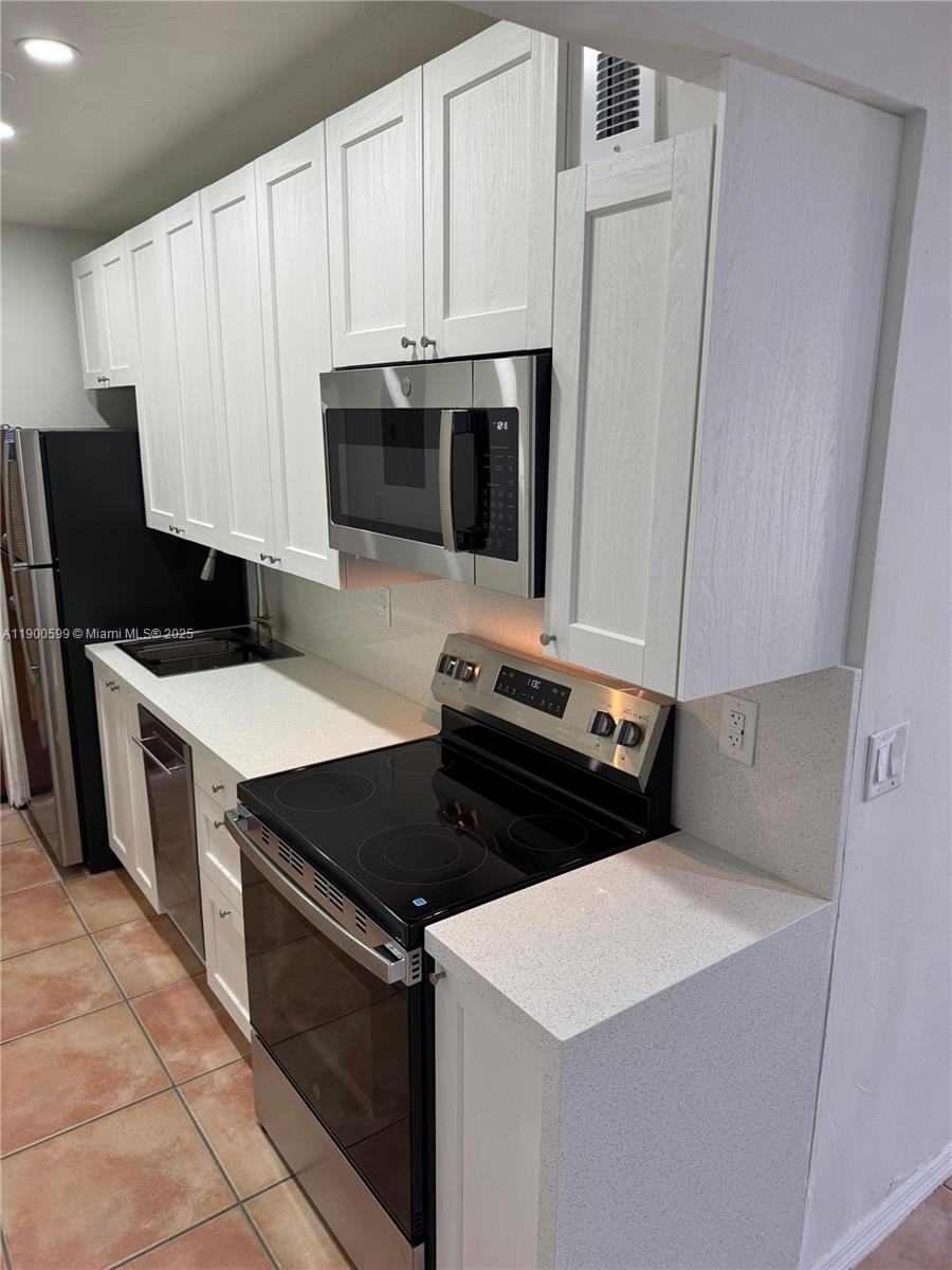 8300 Byron Avenue, Unit 5 Miami Beach, FL 33141 - Photo 5 of 12 a kitchen with a stove and a microwave