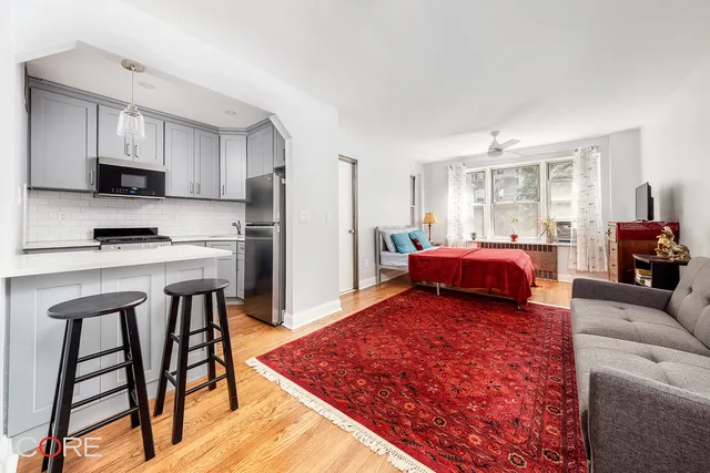 a living room with stainless steel appliances furniture a rug and a kitchen view