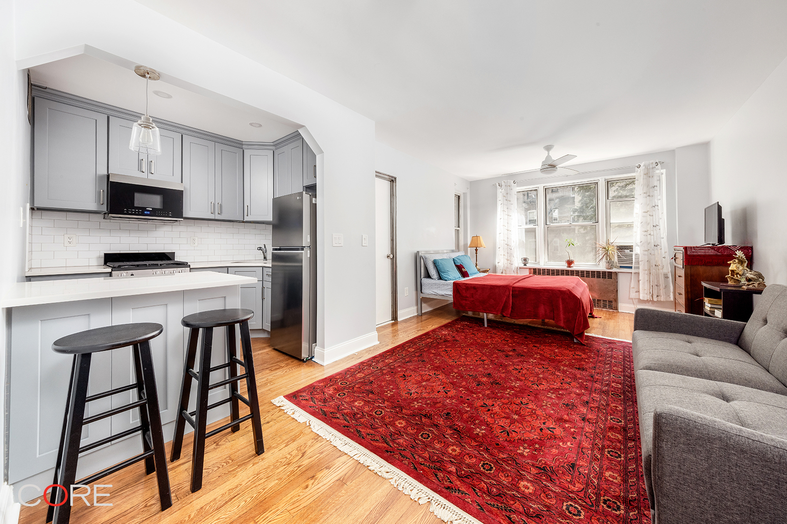 a living room with stainless steel appliances furniture a rug and a kitchen view