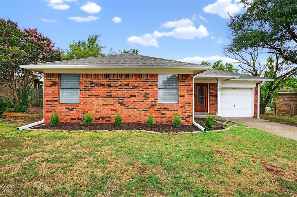 Ranch-style home with roof with shingles, brick siding, a front lawn, driveway, and an attached garage