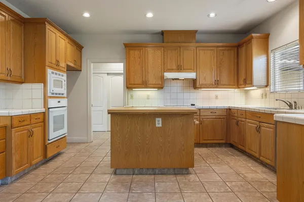 a view of empty room with kitchen and window