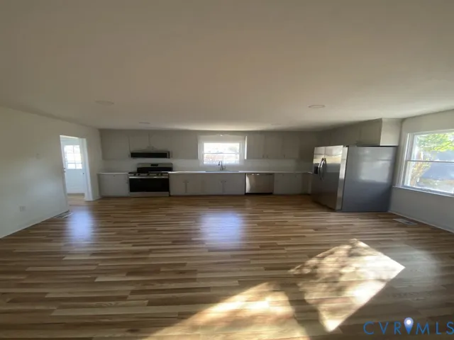 a view of empty room with wooden floor and window