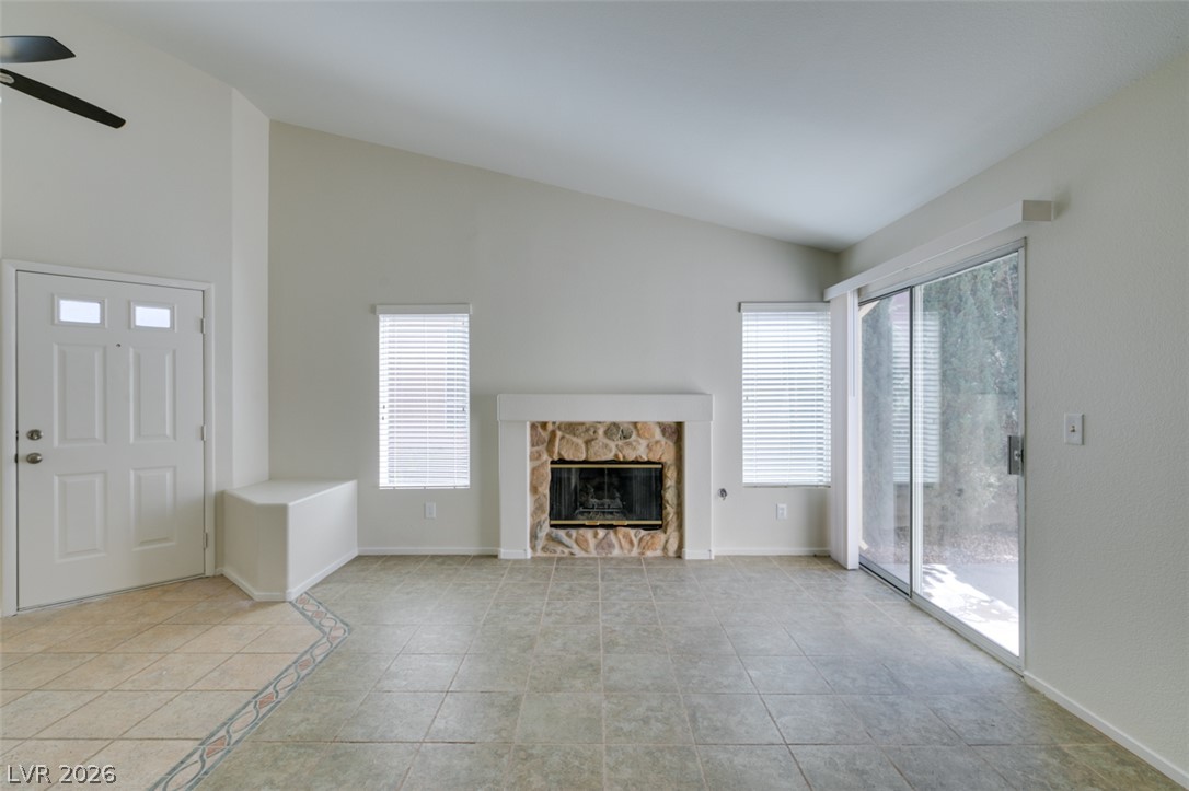 307 Cavalla Street Henderson, NV 89074 - Photo 9 of 44 A cozy living space features vaulted ceilings, a stone-accented fireplace, and backyard access.