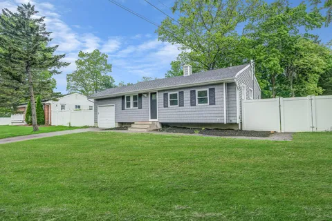 a front view of house with yard and trees in the background