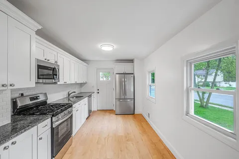 a large kitchen with stainless steel appliances granite countertop a stove a sink dishwasher and a refrigerator with wooden floor