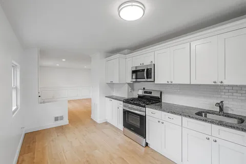 a kitchen with granite countertop white cabinets and stainless steel appliances