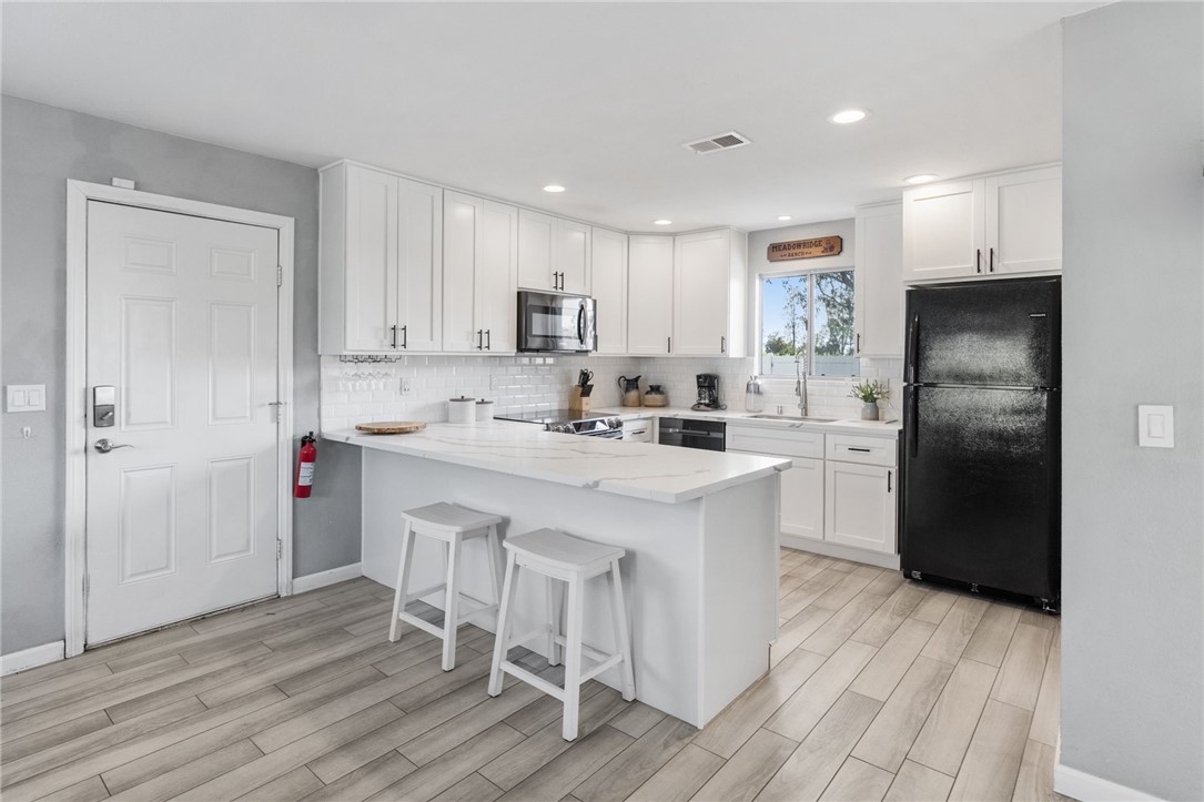 35825 Meadow Ridge Road Temecula, CA 92592 - Photo 34 of 75 a kitchen with stainless steel appliances a refrigerator a sink dishwasher a stove with white cabinets and wooden floor
