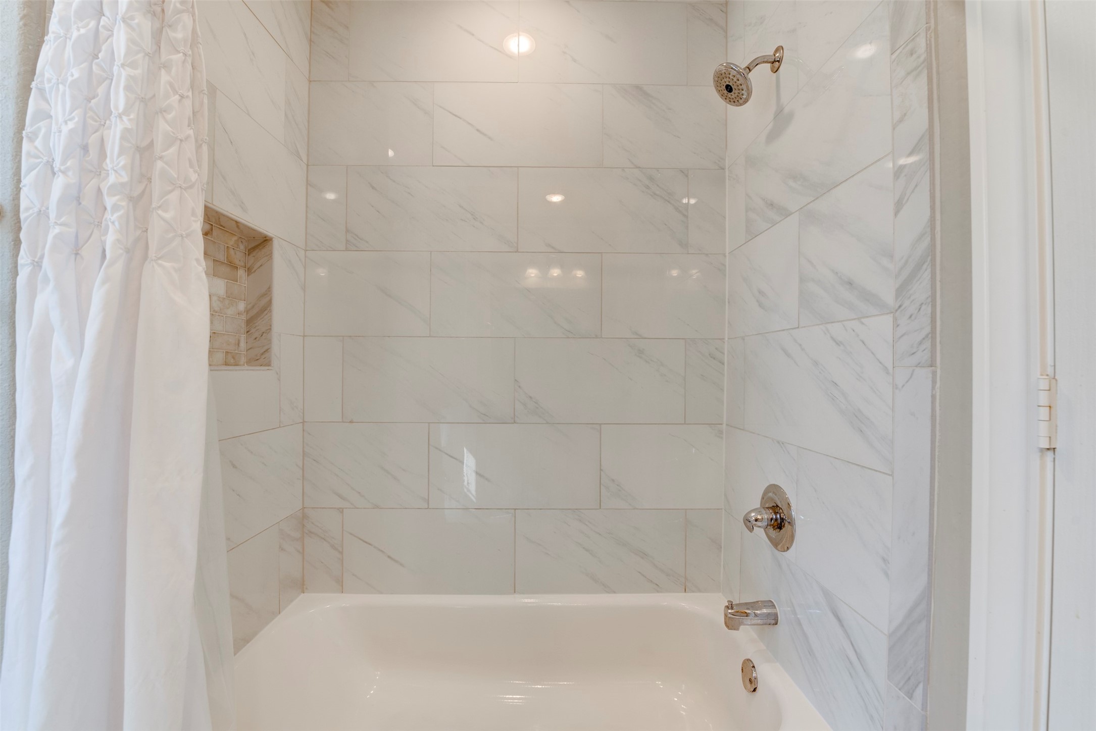 109 Dresden Street Houston, TX 77012 - Photo 34 of 43 This bathroom features a modern bathtub with elegant white marble tiles, a built-in shower, and a stylish niche for storage.