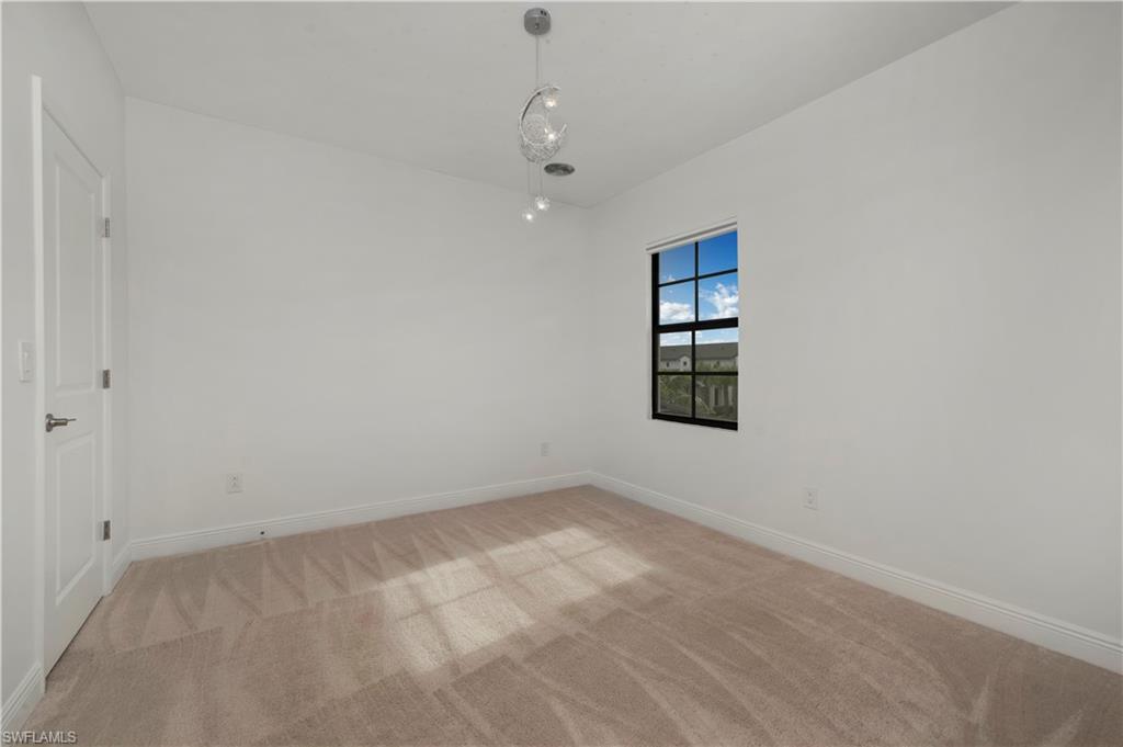 7549 Carnegie Way Naples, FL 34119 - Photo 9 of 22 an empty room with windows and cabinet
