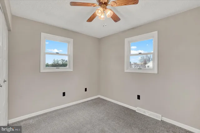 a view of an empty room with window and a ceiling fan