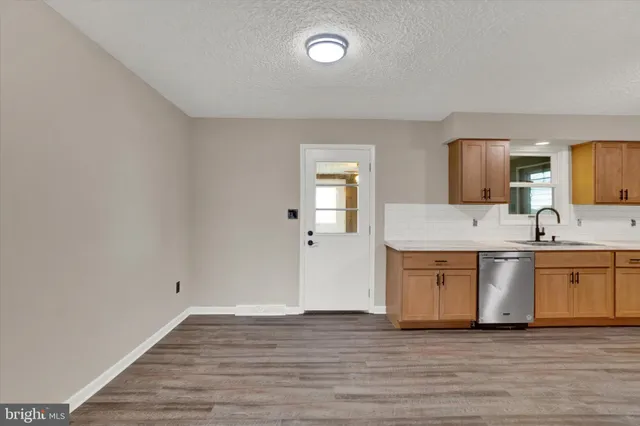 a large kitchen with granite countertop a sink cabinets and wooden floor