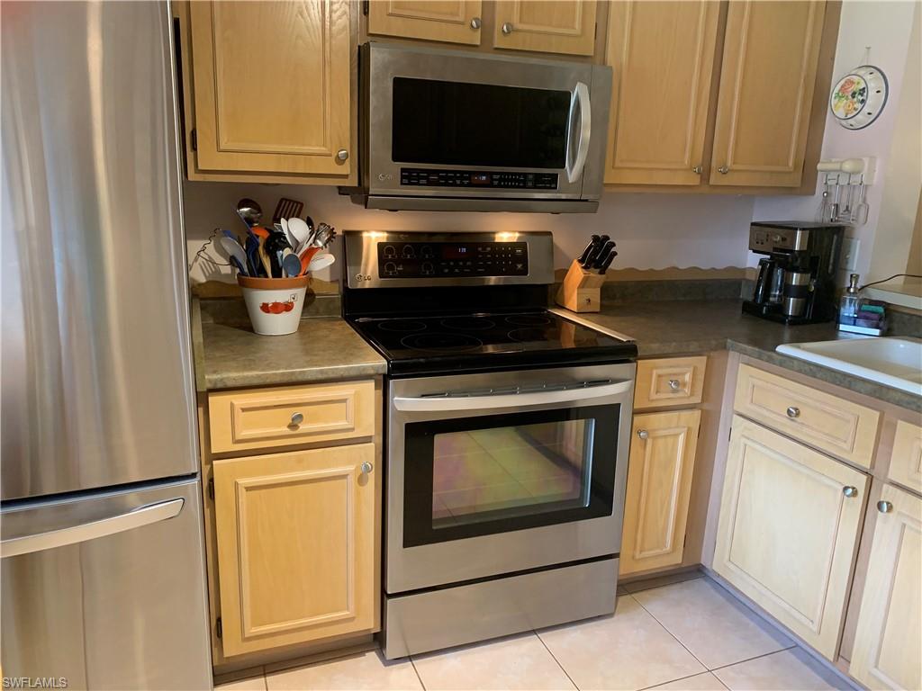 653 Squire Circle, Unit 102 Naples, FL 34104 - Photo 4 of 17 a kitchen with stainless steel appliances granite countertop a stove a microwave and a refrigerator