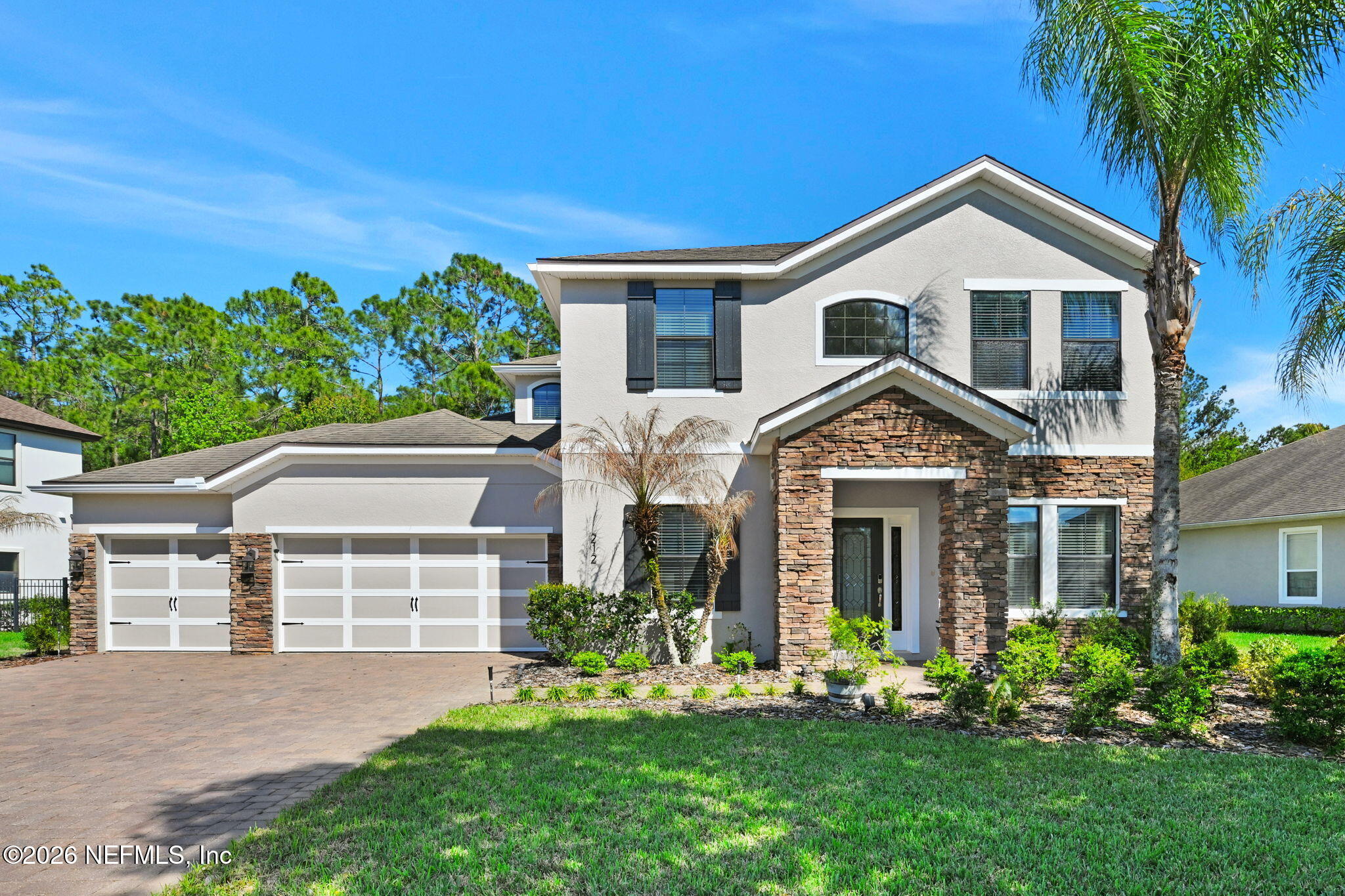 a front view of a house with a yard and potted plants