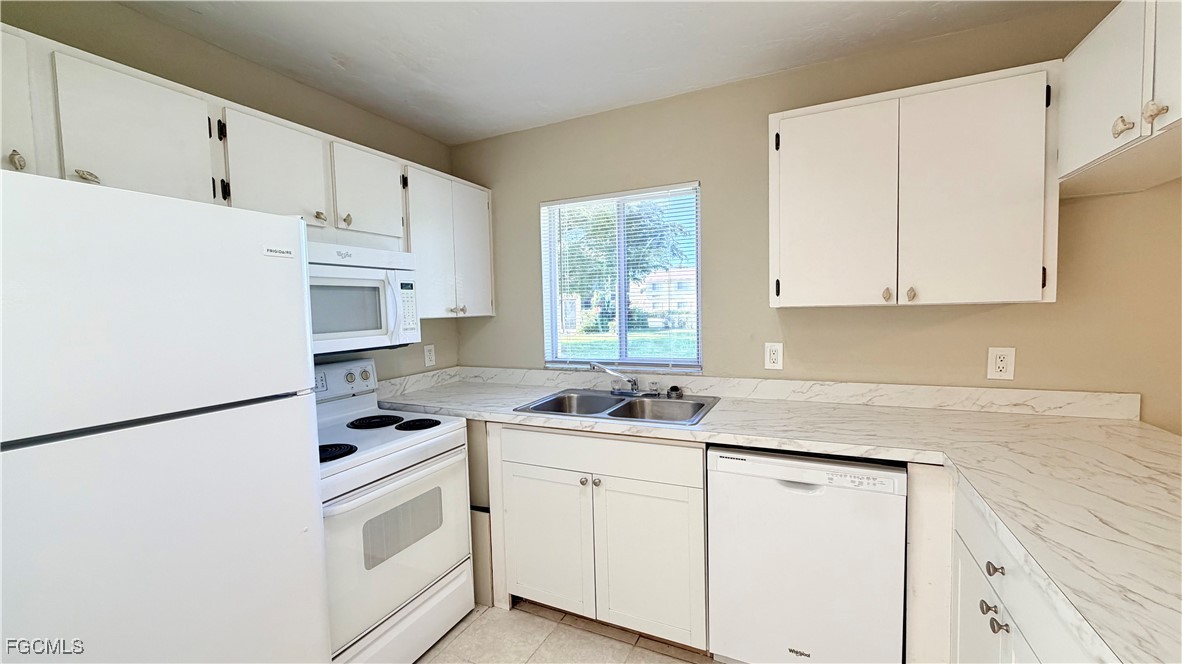8049 Country Road, Unit 101 Fort Myers, FL 33919 - Photo 7 of 19 a kitchen with granite countertop white cabinets and white appliances