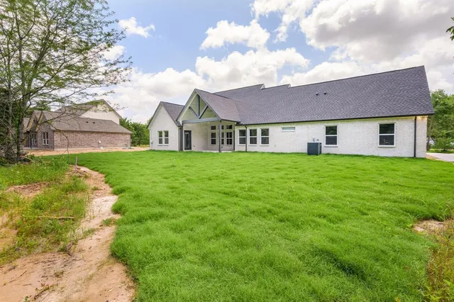 a view of a house with a yard and large trees