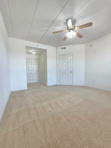 a view of an empty room and chandelier fan