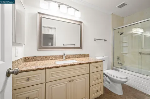a bathroom with a granite countertop toilet sink and a mirror