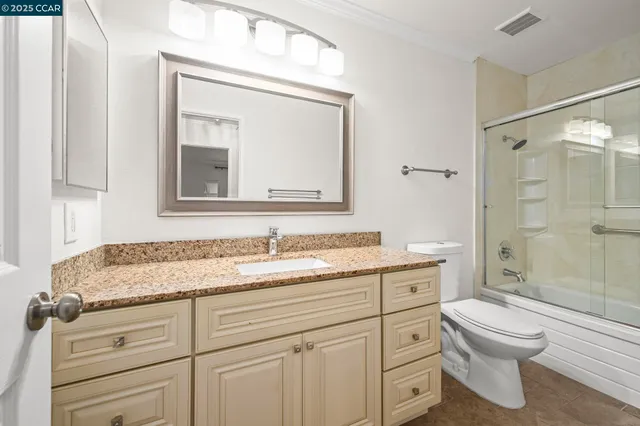 a bathroom with a granite countertop toilet sink and a mirror