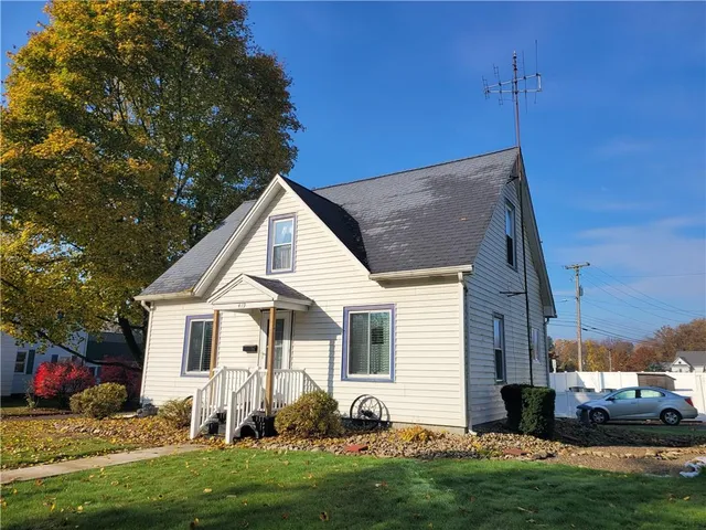 a view of a white house with a big yard and potted plants