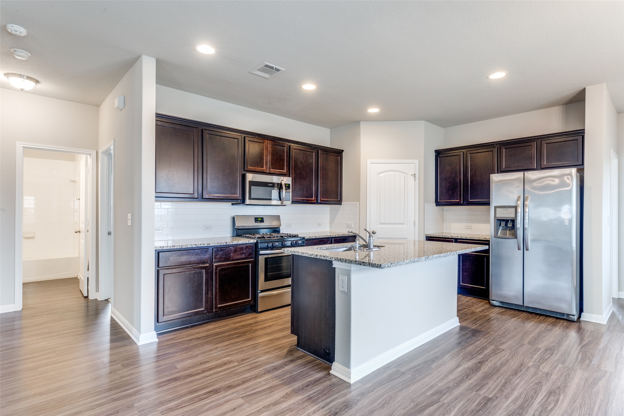 348 Shiner Lane Georgetown, TX 78626 - Photo 12 of 37 a kitchen with stainless steel appliances granite countertop a refrigerator stove a sink and a microwave oven with wooden floor
