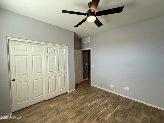 an empty room with wooden floor closet fan and windows