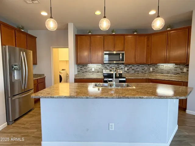 a kitchen with stainless steel appliances granite countertop a sink a refrigerator and a microwave