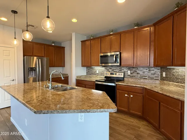 a kitchen with kitchen island granite countertop a sink a counter top space appliances and cabinets