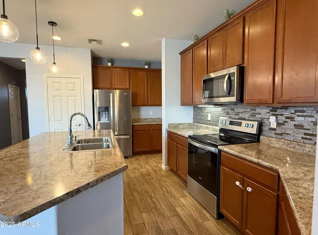 a kitchen with kitchen island granite countertop stainless steel appliances and sink
