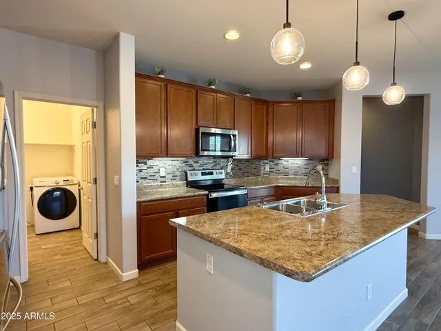 a kitchen with stainless steel appliances granite countertop a sink a stove and refrigerator