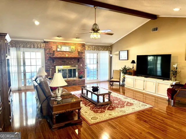 a living room with furniture a flat screen tv and floor to ceiling window