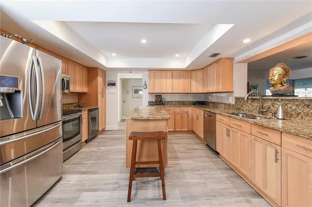 a large kitchen with stainless steel appliances kitchen island granite countertop a stove a sink dishwasher and a refrigerator