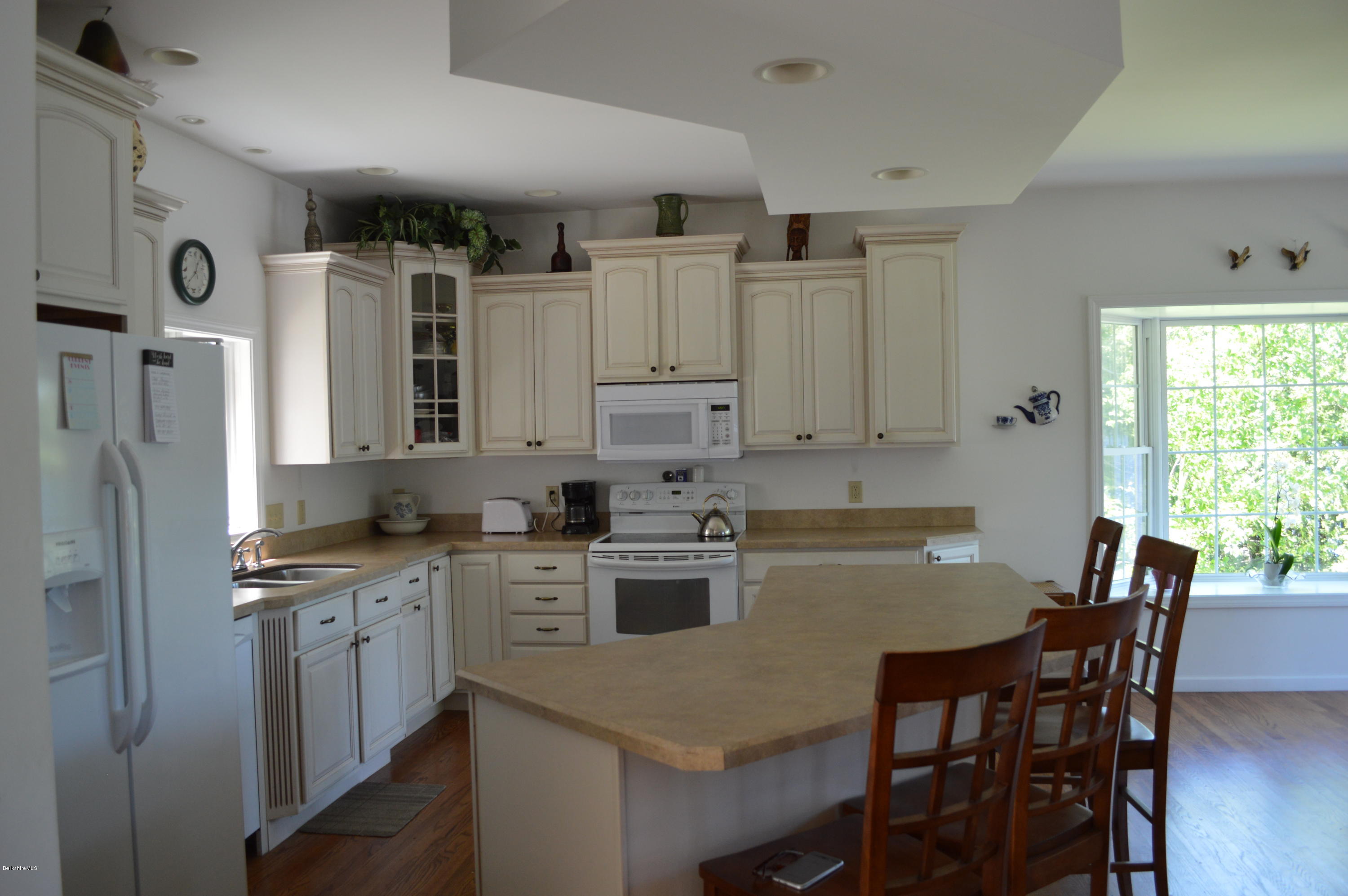 1381 East Otis Road Otis, MA 01029 - Photo 10 of 48 a kitchen with stainless steel appliances granite countertop a stove top oven a refrigerator a dining table and chairs with wooden floor
