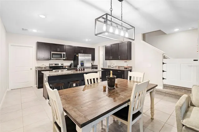 a kitchen with stainless steel appliances granite countertop a refrigerator a stove a sink a microwave and a dining table with wooden floor