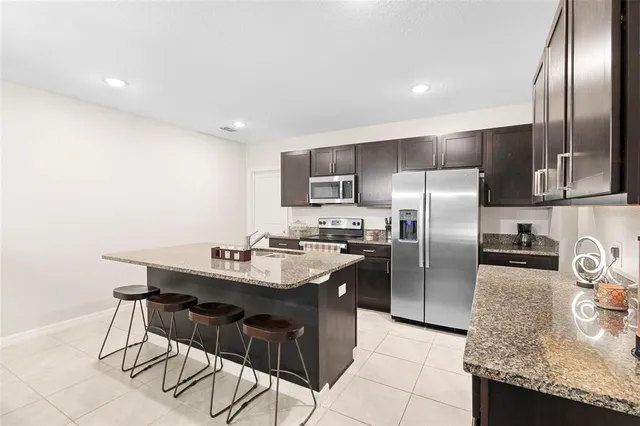 a kitchen with kitchen island granite countertop a sink refrigerator and microwave