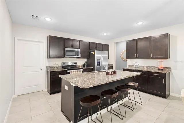 a kitchen with stainless steel appliances granite countertop a stove a sink a microwave a refrigerator and cabinets