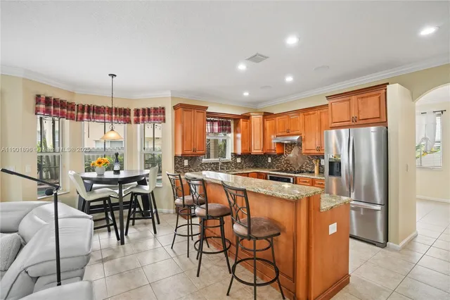 a kitchen with stainless steel appliances granite countertop table chairs and a refrigerator