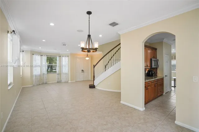 a view of an empty room and kitchen with windows