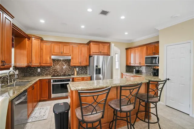 a kitchen with stainless steel appliances granite countertop a stove a sink dishwasher and a refrigerator